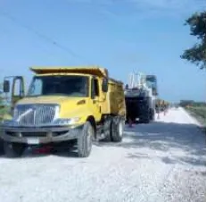 Camión de volteo y equipo de pavimentación sobre un camino en construcción