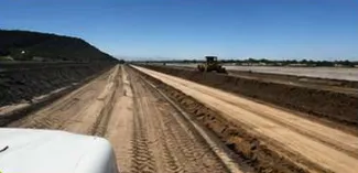 Terracería recién conformada con una motoconformadora trabajando al fondo