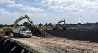 Excavadoras y camión de volteo cargando material en un frente de terracería